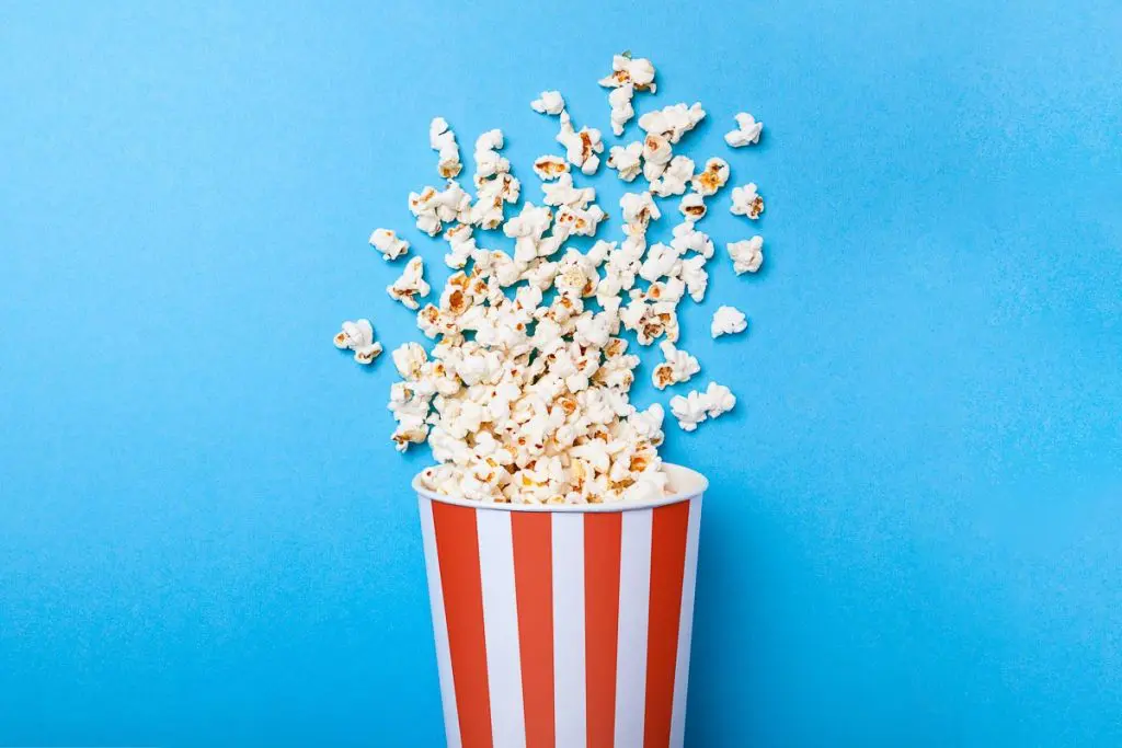 movie theater popcorn in red and white striped carton on blue background