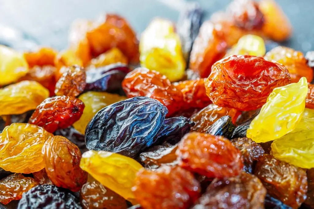 purple, orange, and yellow raisins in a pile